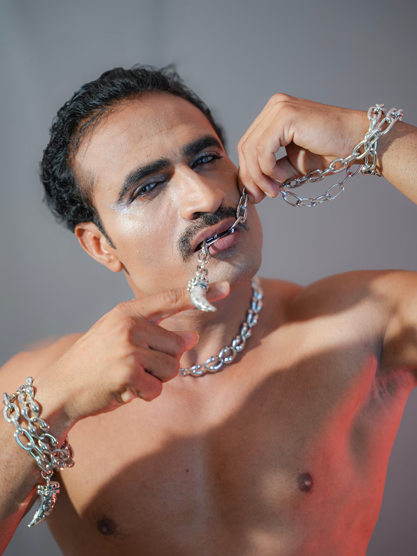 Man wearing silver jewelry against a neutral background
