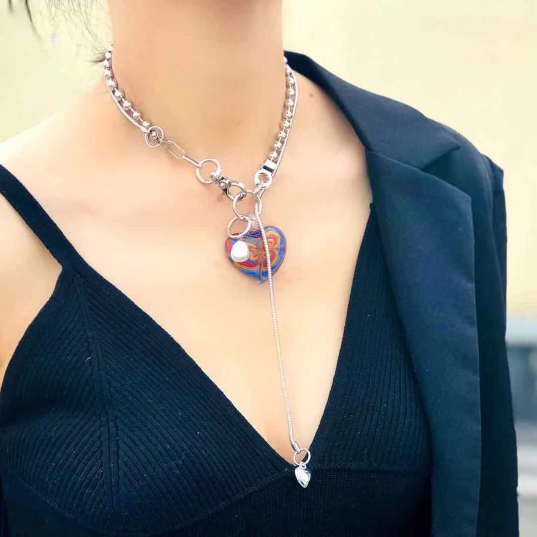 Person wearing a silver necklace with a heart pendant
