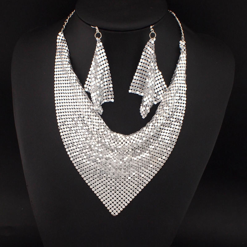 Silver mesh triangle necklace and matching earrings displayed on black bust – statement jewelry set for formal or pride occasions.
