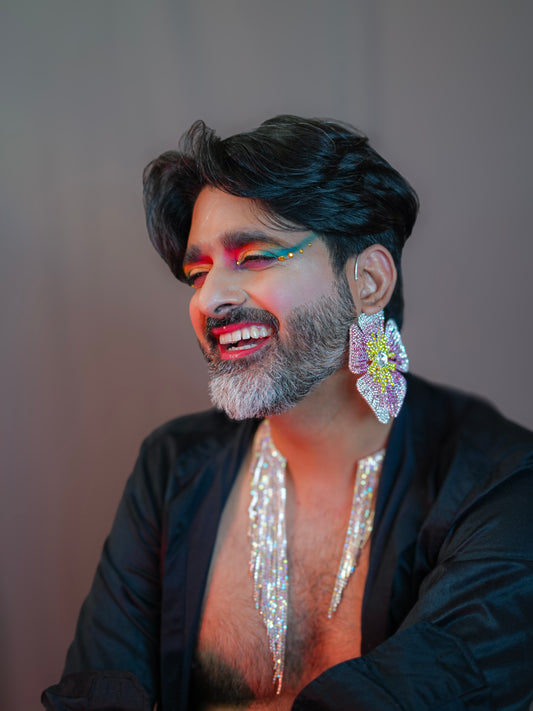 Person wearing Infae Earrings—large floral statement jewelry with pink, silver, and yellow petals and a central gem, styled with puffed sleeves and metallic accents