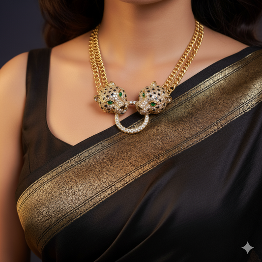 Gold statement necklace with two panther heads adorned in green and white stones, connected by a central ring, worn over a black and gold saree.