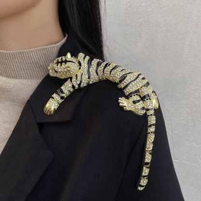 Gold tiger brooch on a black coat against a neutral background