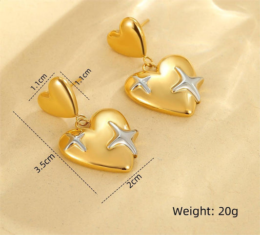 Gold double heart earrings with silver star embellishments – 3.5 cm long statement studs with 20g weight, displayed on beige surface.